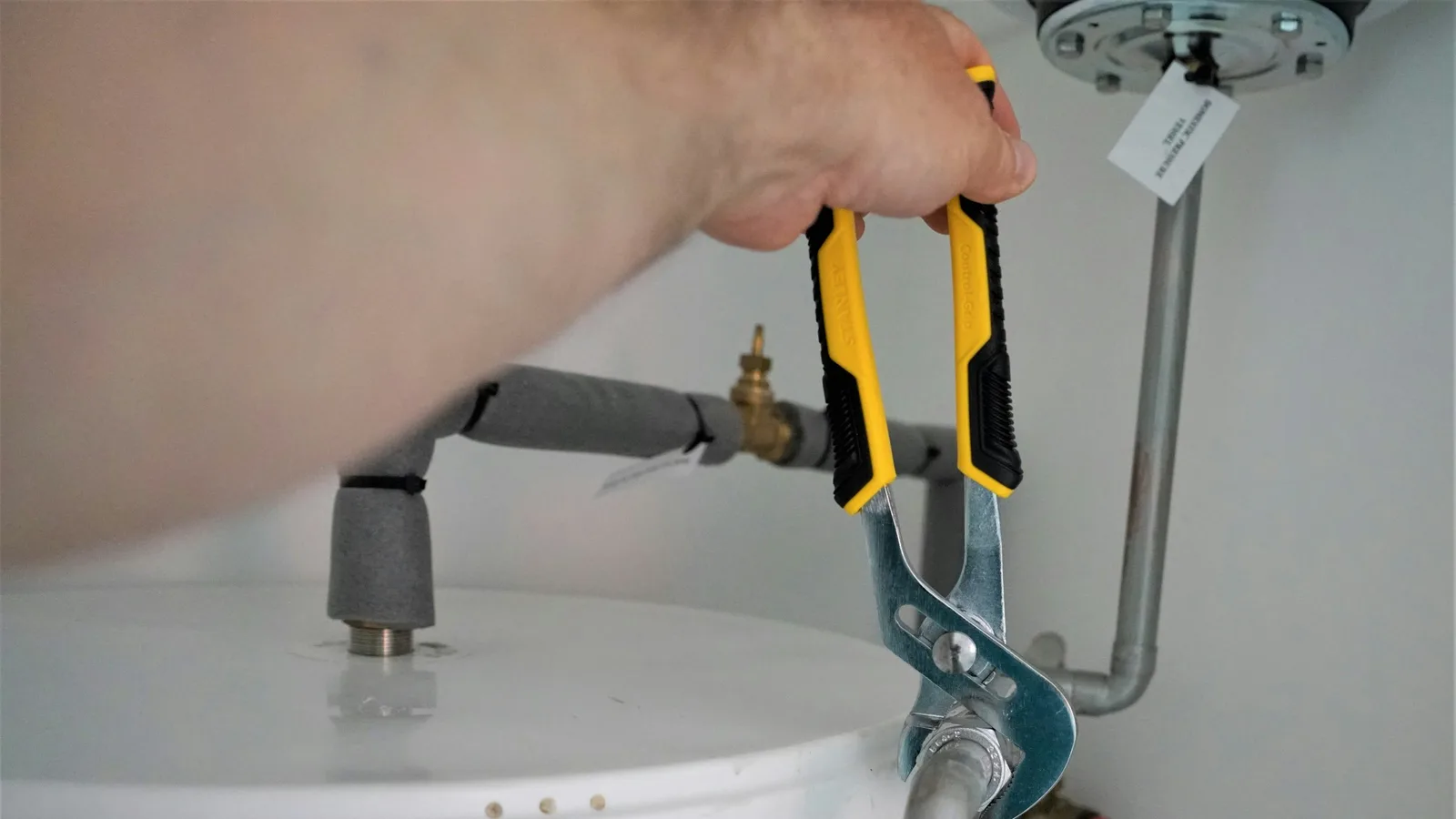 A residential water heater being serviced, with the drain valve and connections visible